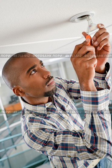 man is replacing a light bulb. Стоковое фото, агентство Ingram Publishing / Фотобанк Лори