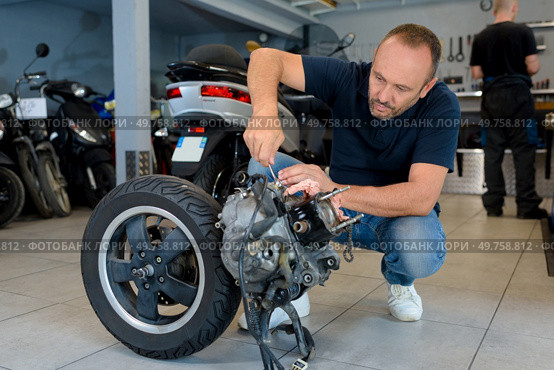 man looking at dismantled scooter engine in garage. Стоковое фото, агентство Ingram Publishing / Фотобанк Лори