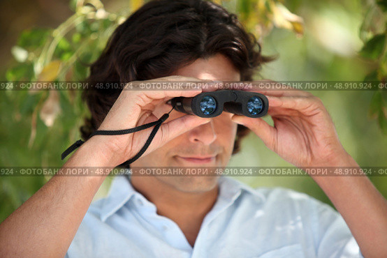 Man looking through a pair of binoculars. Стоковое фото, агентство Ingram Publishing / Фотобанк Лори