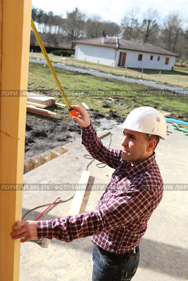 Man measuring wood beam. Стоковое фото, агентство Ingram Publishing / Фотобанк Лори