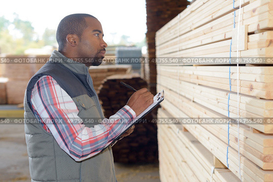 Man noting wood reference onto clipboard. Стоковое фото, агентство Ingram Publishing / Фотобанк Лори