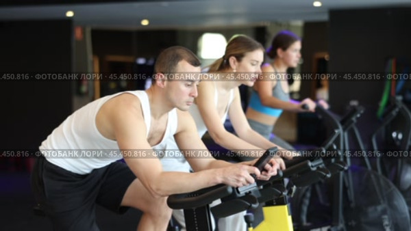 Man performs exercises with stationary bicycle in gym. Стоковое видео, видеограф Яков Филимонов / Фотобанк Лори