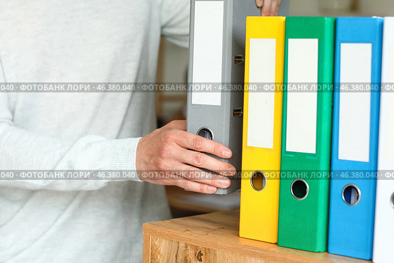 Man putting folder with documents on shelf in office. Стоковое фото, фотограф Pixel_shot / Фотобанк Лори