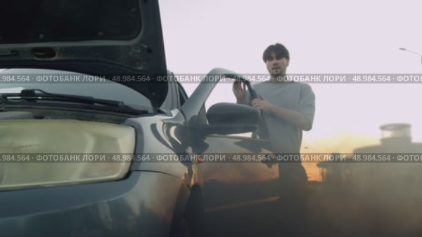Man started car, but it began to smoke and burn. In panic, he ran to check engine and look under hood to find cause of problem. Стоковое видео, видеограф Strunov David / Фотобанк Лори