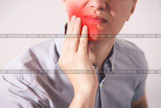 Man suffering from a toothache on gray background. Стоковое фото, фотограф Станислав Тарко / Фотобанк Лори