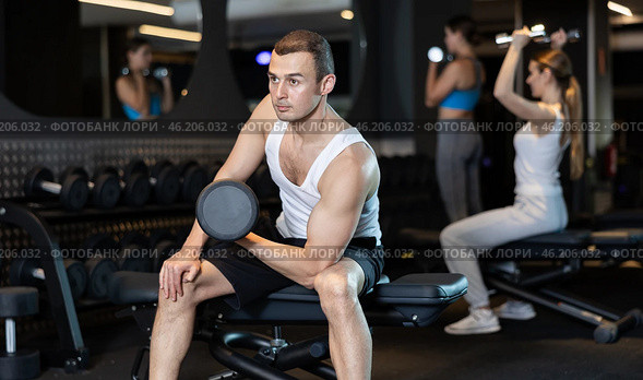 Man trains muscles of arms and back using dumb-bell shaped figure weighting. Стоковое фото, фотограф Яков Филимонов / Фотобанк Лори