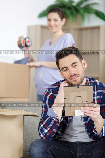man unpacking photos at new home. Стоковое фото, агентство Ingram Publishing / Фотобанк Лори