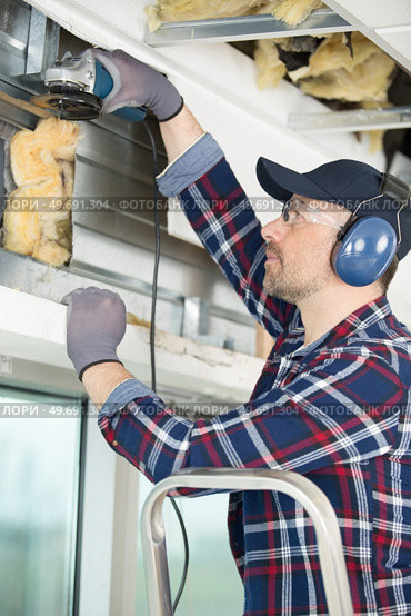 man using a grinder on a window. Стоковое фото, агентство Ingram Publishing / Фотобанк Лори