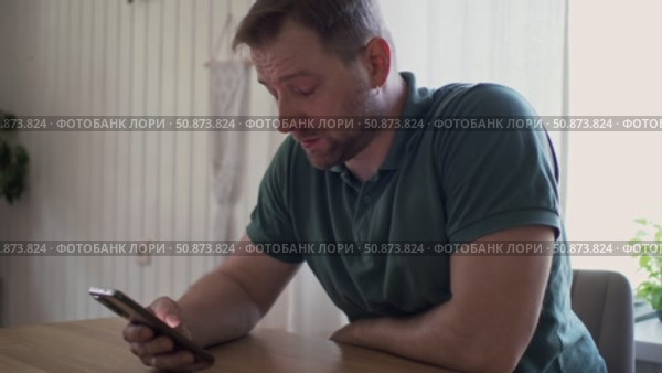 Man using his cellphone. Handsome guy use mobile phone at home. Male browses social networks, gaming, does shopping online, chats with friends, writes or reads messages. Close up. 4k video footage. Стоковое видео, видеограф Марина Демидюк / Фотобанк Лори