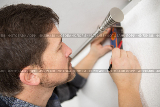 man using spirit level to check curtain rail. Стоковое фото, агентство Ingram Publishing / Фотобанк Лори