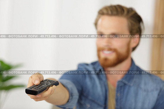 man with remote control switches channels on the tv. Стоковое фото, агентство Ingram Publishing / Фотобанк Лори