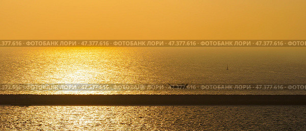 Manama, Bahrain - Jan 08 2024, Panorama of the sea at dawn, sunrise, morning, a small boat sailing along the long pier, Manama, Bahrain. Стоковое фото, фотограф Сергей Богомяко / Фотобанк Лори