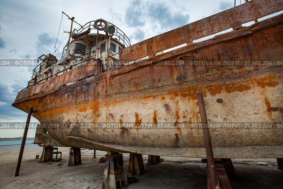 Mangystau, Kazakhstan - May 19, 2012: Old rusted ship on Caspian Sea, Bautino bay, ship-repairing yard. Grey cloudy sky. Стоковое фото, фотограф Alexey Rezvykh / Фотобанк Лори