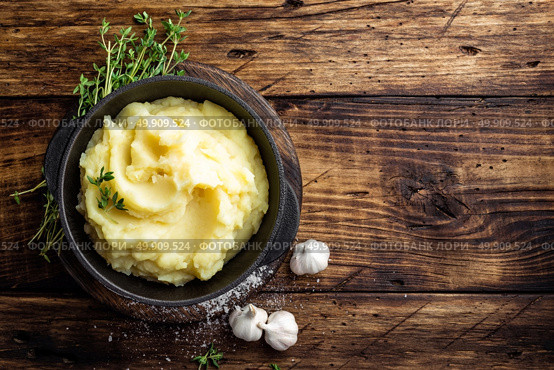 Mashed potatoes, boiled puree in cast iron pot on dark wooden rustic background, top view. Стоковое фото, агентство Ingram Publishing / Фотобанк Лори