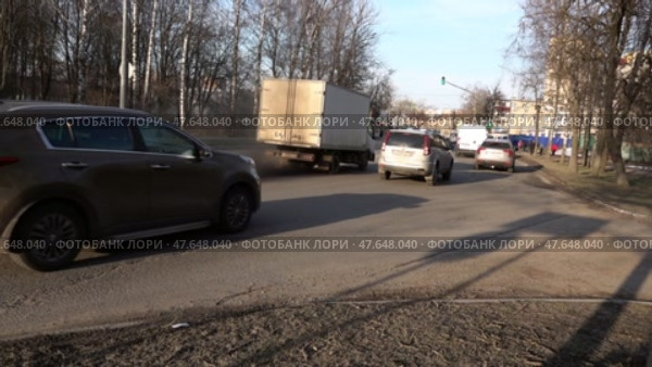 Машины едут по дороге в городе на зеленый сигнал светофора на закате солнца. Весна. Апрель. Cars drive along the road in the city at a green traffic light at sunset. Spring. April. Редакционное видео, видеограф Горшков Александр / Фотобанк Лори