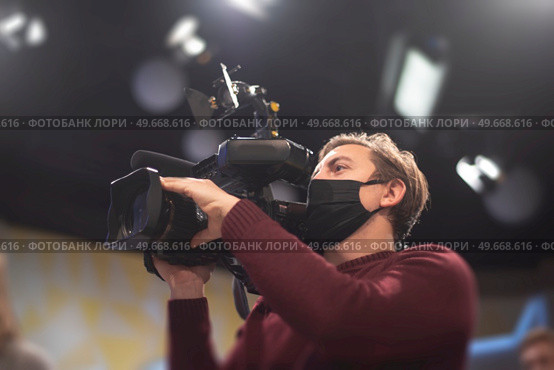 masked cameraman is filming a television show in the studio. TV. Стоковое фото, агентство Ingram Publishing / Фотобанк Лори
