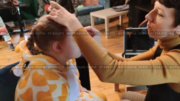 Мастер рисует аквагрим на лице ребенку.The master draws an aquagrim on the child's face. Редакционное видео, видеограф Мария / Фотобанк Лори