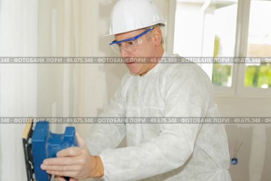 mature contractor sanding wall. Стоковое фото, агентство Ingram Publishing / Фотобанк Лори