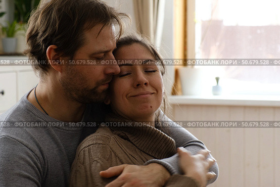 Mature couple hugging hugging each other kissing at home bedroom. Intimate Moment. Tender embrace shared between a loving middle age man and woman, husband and wife. Deep love. Low key, cinematic. Стоковое фото, фотограф Марина Демидюк / Фотобанк Лори