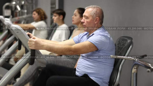 Mature man riding cardiovascular trainers in modern gym. Стоковое видео, видеограф Яков Филимонов / Фотобанк Лори