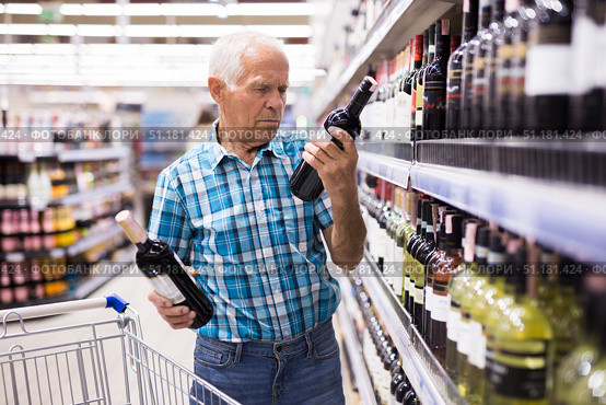 mature senor choosing alcoholic drinks in supermarket. Стоковое фото, фотограф Татьяна Яцевич / Фотобанк Лори