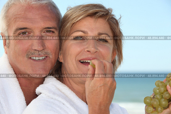 mature woman in bathrobe at spa resort eating grapes with husband. Стоковое фото, агентство Ingram Publishing / Фотобанк Лори