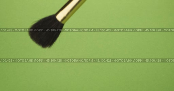 Мазки кистью для макияжа на зеленом фоне. Выделена рука, держащая кисточку для макияжа. Крупный план. Стоковое видео, видеограф Александр Собко / Фотобанк Лори