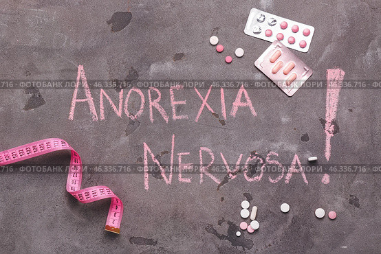 Measuring tape and pills with text ANOREXIA NERVOSA on grunge background. Стоковое фото, фотограф Pixel_shot / Фотобанк Лори