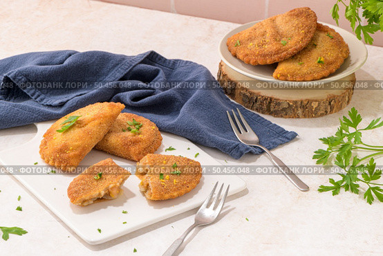Meat patties and parsley leaves on white ceramic dishes in a kitchen counter top. Стоковое фото, агентство Ingram Publishing / Фотобанк Лори
