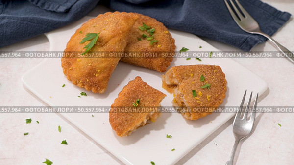 Meat patties and parsley leaves on white ceramic dishes in a kitchen counter top. Стоковое фото, агентство Ingram Publishing / Фотобанк Лори