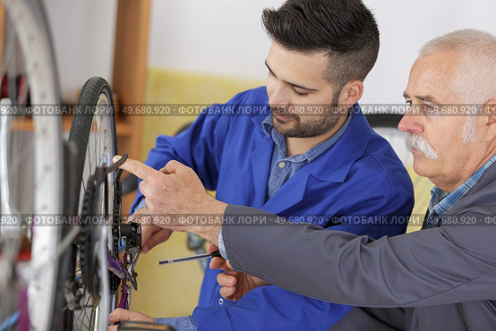 Mechanic checking chain tautness on bicycle. Стоковое фото, агентство Ingram Publishing / Фотобанк Лори