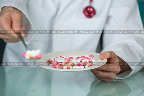 Medic holding tablets forward on a spoon. Стоковое фото, агентство Ingram Publishing / Фотобанк Лори