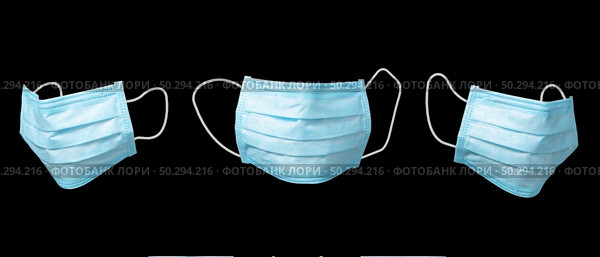 Medical set from three antibacterial protective blue face masks on a black background, copy space. Concept of prevention from respiratory sickness and viruses.. Three flying medical masks against black background. Стоковое фото, агентство Ingram Publishing / Фотобанк Лори
