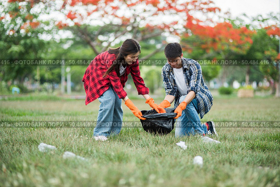 Men and women helped to collect garbage in a black bag. Стоковое фото, агентство Ingram Publishing / Фотобанк Лори