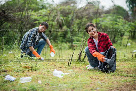 Men and women helped to collect garbage in a black bag. Стоковое фото, агентство Ingram Publishing / Фотобанк Лори