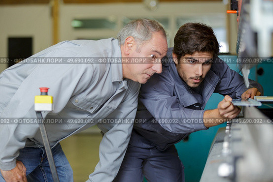 metal craftsman teaching know-how to young man. Стоковое фото, агентство Ingram Publishing / Фотобанк Лори