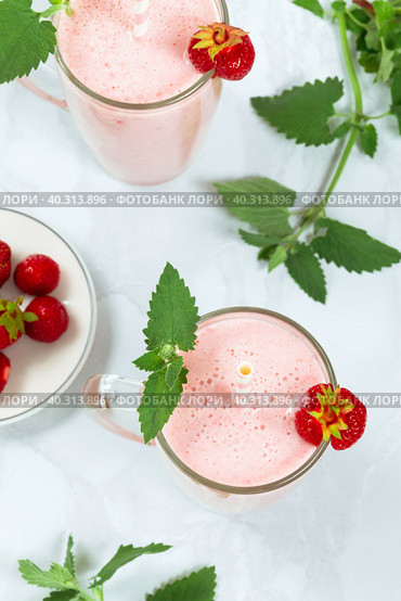 Milkshake with strawberries in a glass glass with melissa leaves in the design, top view. Стоковое фото, фотограф Неведицына Елена / Фотобанк Лори