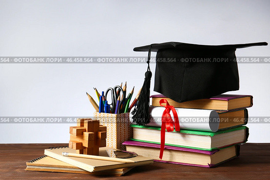Минометная доска, диплом, канцелярские товары и книги на столе. Концепция окончания средней школы. Стоковое фото, фотограф Pixel_shot / Фотобанк Лори