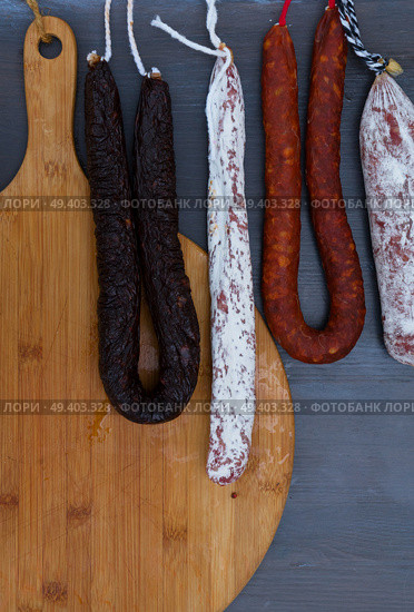 Mix of Cured meat and sausages hanging on dark wooden background. Cured meat and sausages. Стоковое фото, агентство Ingram Publishing / Фотобанк Лори