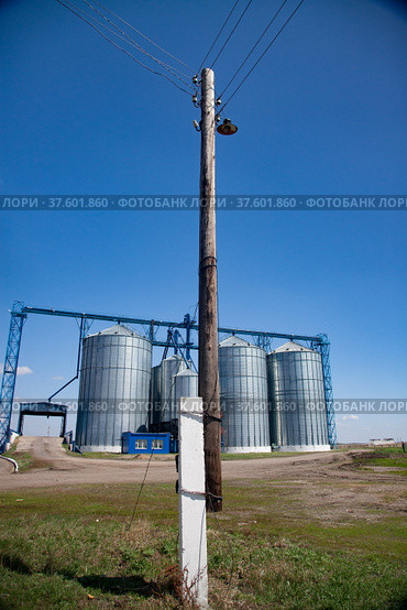 Modern grain storage elevator (on background) and vintage wooden electric pole on front. Стоковое фото, фотограф Alexey Rezvykh / Фотобанк Лори