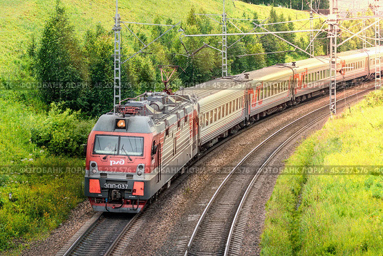 Modern Passenger Train on Scenic Railway Track in Rural Landscape surrounded by nature and trees Electric train, Russian Railways Krasnoyarsk, Russia, July 27, 2024. Редакционное фото, фотограф Владимир Разгуляев / Фотобанк Лори