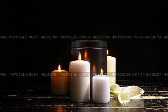 Mortuary urn, burning candles and flowers on table against dark background. Стоковое фото, фотограф Pixel_shot / Фотобанк Лори