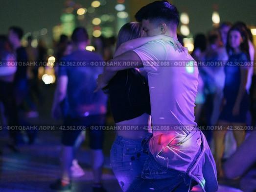 Moscow, Russia - August 20, 2019: Defocused photography of beautiful dancing people on the night party in the city street in  summer night.  Leisure, happiness and entertainment theme. Редакционное фото, фотограф YuryKara / Фотобанк Лори