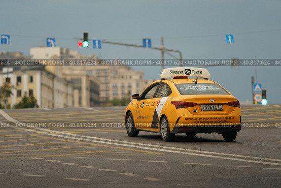 Moscow, Russia - July 10, 2022: Yellow taxi at the city street in sunny summer day. Time before the rain. Concept of the lifestyle of the big city. Close up. back. Rear view. Редакционное фото, фотограф YuryKara / Фотобанк Лори