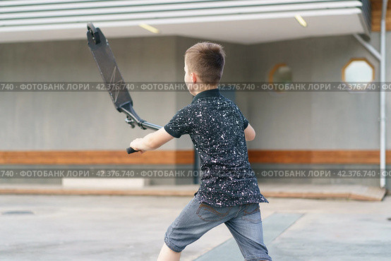 Moscow, Russia - July 26, 2019 Teenager ready to perform a trick at sportive push scooter on a city street. Редакционное фото, фотограф YuryKara / Фотобанк Лори