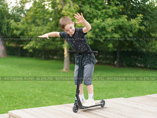Moscow, Russia - July 26, 2019 Trick at sportive push scooter on a city street. Редакционное фото, фотограф YuryKara / Фотобанк Лори