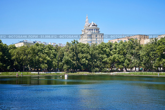 Moscow, Russia. - May 29, 2025: Patriarch's Ponds. "The Patriarch" apartment building is visible in the distance. Редакционное фото, фотограф Наталия Кирсанова / Фотобанк Лори