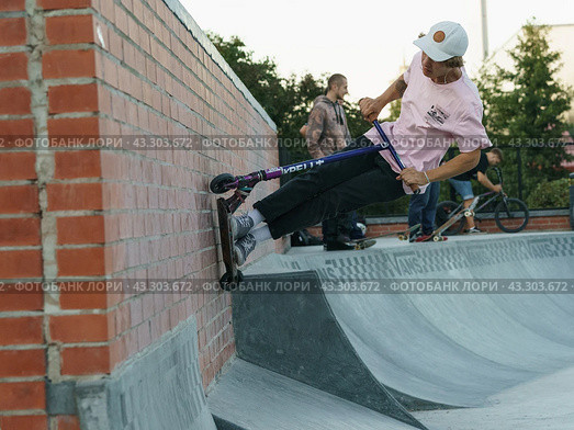 Moscow, Russia - September 29, 2021: Teenager performs trick in the city skate park. Push scooter. Vertical wall riding. Extreme sports is popular among youth. Редакционное фото, фотограф YuryKara / Фотобанк Лори