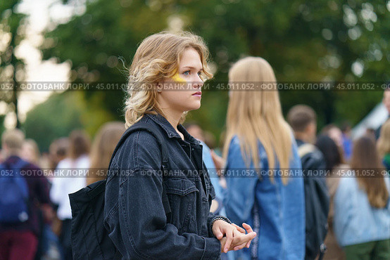 Moscow, Russia - September 5, 2019: Portrait of young woman with yellow stripe on the face on the city festival in the Gorky park. A crowd of youth with smartphones around her. Blurred background. Редакционное фото, фотограф YuryKara / Фотобанк Лори