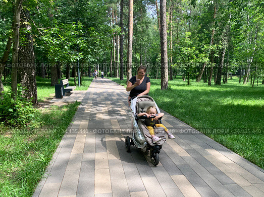 Московская область, город Балашиха. Молодая мама с ребенком в коляске гуляет по тенистой аллее в парке "Пехорка" летом (2020 год). Редакционное фото, фотограф Овчинникова Ирина / Фотобанк Лори